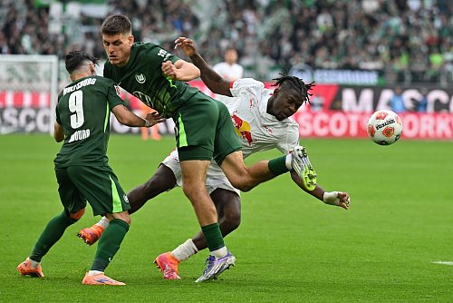 Kaum zu stoppen: Leipzigs Torschütze Johan Bakayoko (r) wird von den Wolfsburgern Joakim Maehle und Mohammed Amoura bedrängt. - © Swen Pförtner/dpa