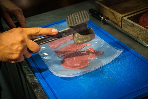 Zwischen zwei Folien gelegt klopft René Tepper in der Küche vom «The Dry Gin and Beef Club» mit einem Fleischhammer die Rinderfilet-Scheiben - bis sie etwa die dreifache Größe erreicht haben. - © Christin Klose/dpa-tmn