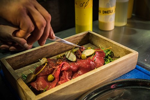 Die Carpaccio-Scheiben werden auf dem Rucola-«Gebirge» angerichtet und mit Oliven, Kapernäpfeln und getrockneten Tomaten getoppt - immer dort, wo der Berg kleine Täler hinterlassen hat. - © Christin Klose/dpa-tmn
