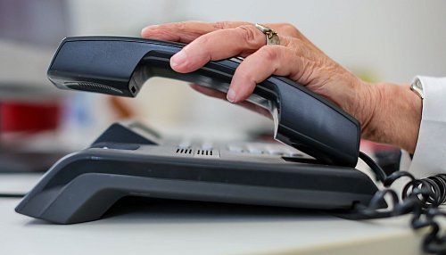 Eine Frau nimmt einen Telefonhörer in die Hand. - © Jan Woitas/dpa