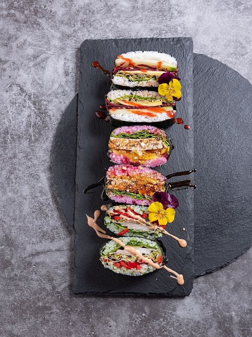 Wer sich für die Vorbereitung etwas mehr Zeit nimmt, kann Sushi-Sandwiches mitbringen - ein hier noch mit essbaren Blüten verzierter Hingucker. - © Alex Neumayer/Christian Verlag/dpa-tmn