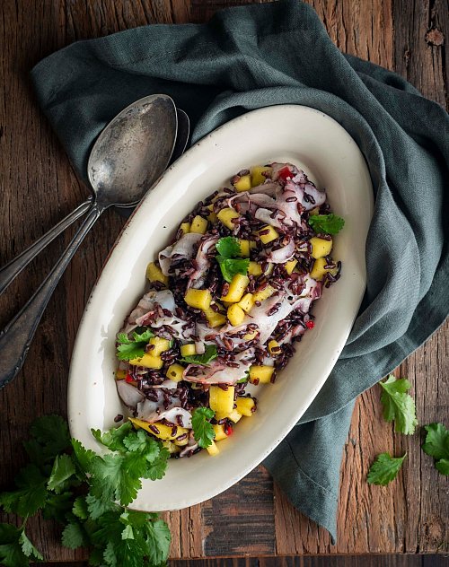 Wenn es mal etwas ganz Exotisches sein soll: Dieser schwarze Reissalat mit Mango und Oktopus sticht auf einer Mitbringfeier sicher heraus. - © Valerie Hammacher/ars vivendi/dpa-tmn