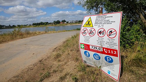 Ein Schild an Rheinkilometer 729 in Himmelgeist warnt vor Lebensgefahr im Rhein durch gefährliche Strömung. - © Christoph Reichwein/dpa