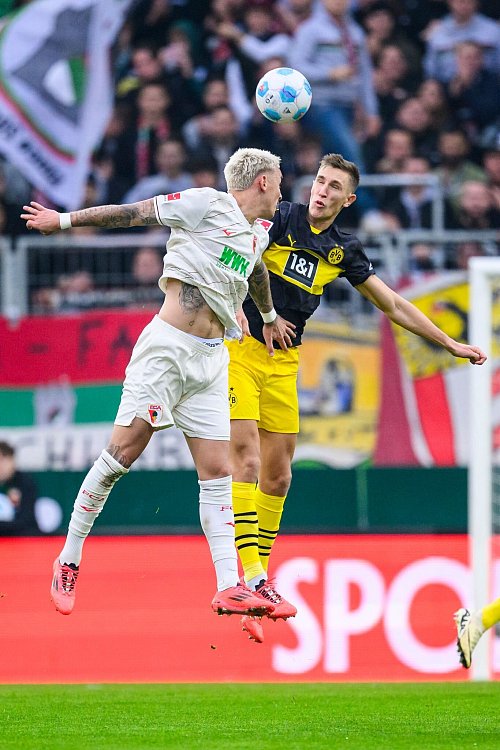 Augsburgs Phillip Tietz (l) und Dortmunds Nico Schlotterbeck im Luftkampf. - © Tom Weller/dpa