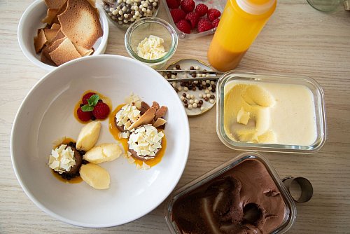 Mangoeis und Schokoladenmousse werden auf Mango- und Erdbeerpüree-Klecksen angerichtet. Splitter von weißer Schokolade und frischen Himbeeren toppen die Kreation. - © Christin Klose/dpa-tmn