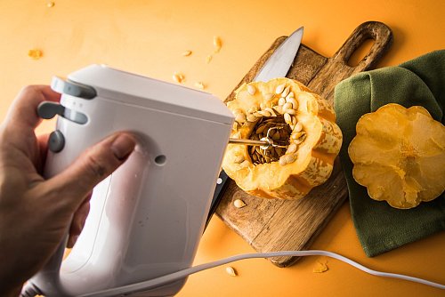 Schritt 2: Den Handmixer durch das Loch in den Kürbis stecken, einschalten und an der Innenwand des Kürbisses entlangführen. - © Christin Klose/dpa-tmn