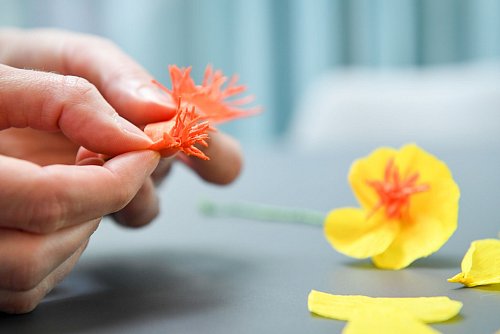 Für die Blütenfüllung den eingeschnittenen Krepppapier-Streifen um den Blumendraht wickeln und alles mit Floristen-Band fixieren. - © Zacharie Scheurer/dpa-tmn