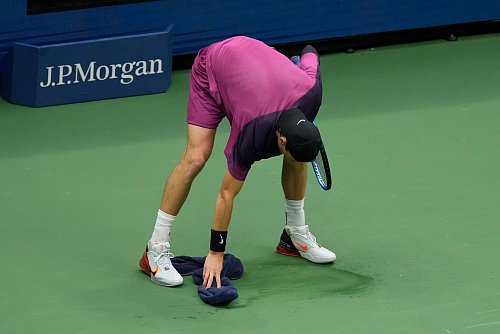 Jack Draper macht mit einem Handtuch den Platz sauber. - © Seth Wenig/AP/dpa