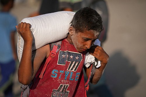 Ein palästinensischer Junge trägt einen Sack Mehl. (Archivbild) - © Jehad Alshrafi/AP/dpa