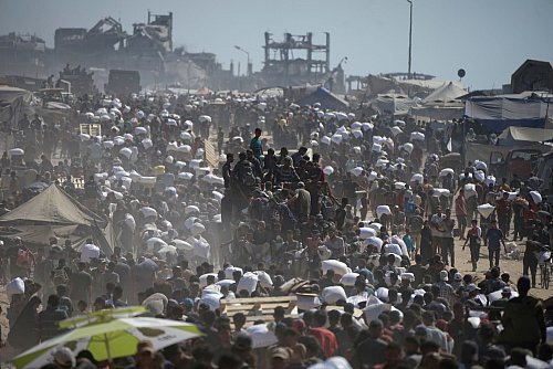 Palästinenser tragen Säcke mit Mehl aus einem Hilfskonvoi. (Archivbild) - © Jehad Alshrafi/AP/dpa