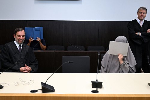 Der Angeklagte und die Mitangeklagte verdecken ihre Gesichter. (Archivbild) - © Federico Gambarini/dpa