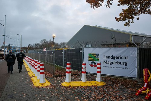 Polizisten laufen vor dem temporären Gerichtsgebäude des Landgerichtes Magdeburg Streife. - © Jan Woitas/dpa