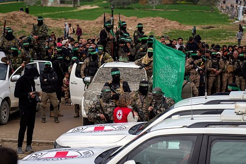 Eine Vertreterin des Roten Kreuzes spricht mit Hamas-Mitgliedern. - © Abdel Kareem Hana/AP/dpa