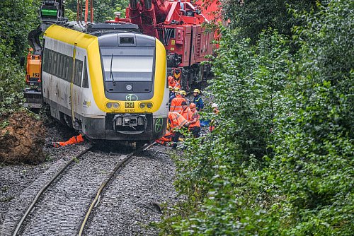 Mit einem Kran wird an der Unfallstelle, an der ein Regionalzug entgleist ist, gearbeitet. Ein Regionalexpress war am Sonntagabend (27.07.2025) in Riedlingen nach bisherigen Erkenntnissen infolge eines Hangrutsches entgleist. - © Jason Tschepljakow/dpa