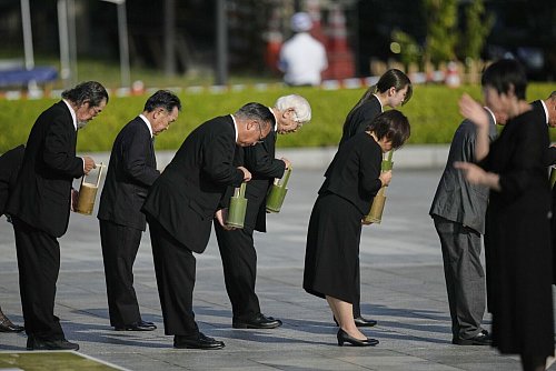 Teilnehmer der Gedenkveranstaltung in Hiroshima halten eine Schweigeminute ab. - © Louise Delmotte/AP/dpa