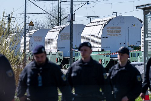 Polizisten sichern einen Zug mit Castor-Behältern ab. - © Armin Weigel/dpa
