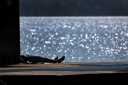 Ausflügler genießen auf dem Steg des Strandbades am Ammersee in Bayern den Sonnenschein. - © Karl-Josef Hildenbrand/dpa