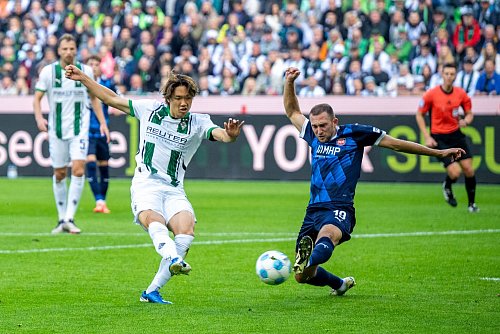 Der Mönchengladbacher Ko Itakura (l) trifft in dieser Szene zum 1:1, Heidenheims Jonas Föhrenbach grätscht zu spät dazwischen. - © David Inderlied/dpa