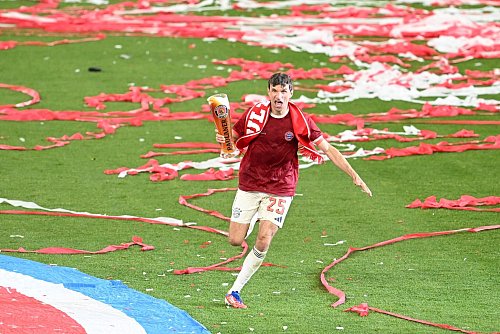 Thomas Müller rennt bei der Meisterfeier mit Bier über das Feld. - © Sven Hoppe/dpa