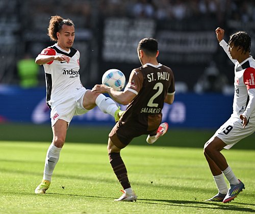 Eintracht Frankfurt um Arthur Theate (l) und der FC St. Pauli mit Manolis Saliakas lieferten sich eine wilde Anfangsphase. - © Arne Dedert/dpa