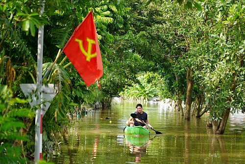 Ein Mann paddelt in der Nähe von Hanoi durch das Hochwasser. - © Hau Dinh/AP/dpa