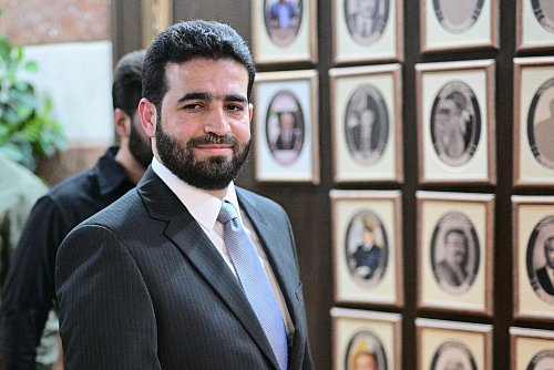 Anas Chattab ist erst seit Ende März Innenminister von Syrien. Hier steht er vor Fotos seiner Vorgänger im Amt. Die Bilder einiger Ex-Minister haben die neuen Machthaber entfernt. - © Sebastian Gollnow/dpa