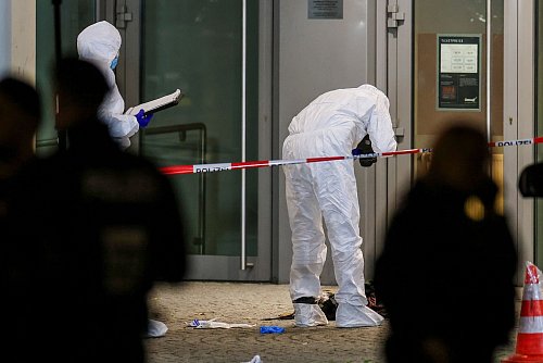 Beamte in weißen Schutzanzügen fotografieren blutige Kleidungsstücke und zertrümmerte Glasscheiben. - © Christoph Reichwein/dpa