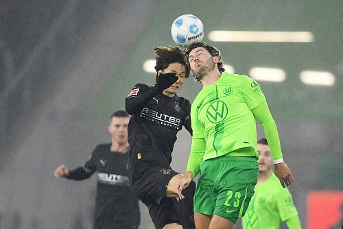 Im Kopfballduell: Wolfsburgs Jonas Wind (r) und Mönchengladbachs Ko Itakura. - © Swen Pförtner/dpa