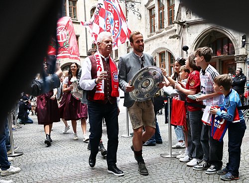 Torjäger Harry Kane trägt die Meisterschale flankiert von Oberbürgermeister Dieter Reiter (l) ins Münchner Rathaus. - © Daniel Löb/dpa