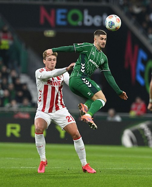 Bremens Romano Schmid (r) geht artistisch zum Ball, der Kölner Sebastian Sebulonsen schaut gebannt zu. - © Carmen Jaspersen/dpa