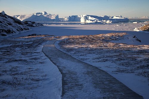 Ein Holzpfad führt durch die Gegend Sermermiut zum Ufer des Ilulissat-Eisfjords. - © Steffen Trumpf/dpa-tmn