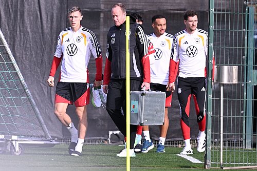 Mit Teamarzt Hahne (2.v.l.) betritt Schlotterbeck (l.) den Trainingsplatz. - © David Inderlied/dpa