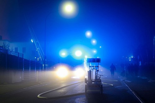 Im dichten Nebel flackert das Blaulicht der Feuerwehrautos bei den Löscharbeiten. - © Christoph Reichwein/dpa