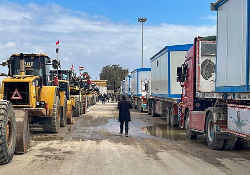 Bulldozer und Lastwagen mit Wohncontainern warten am Rafah-Grenzübergang. (Archivbild) - © Mohamed Arafat/AP/dpa