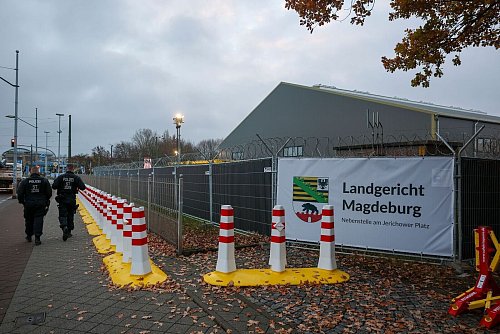 Polizisten laufen vor dem temporären Gerichtsgebäude des Landgerichtes Magdeburg Streife. - © Jan Woitas/dpa