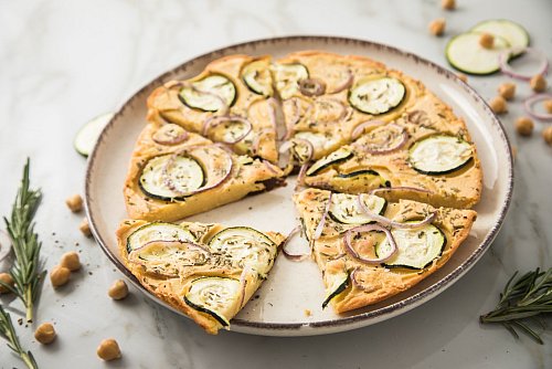 Ohne Fleisch muss bei einem Essen nicht unbedingt etwas fehlen, wie bei dieser Pizza aus Kichererbsenmehl, die mit Zucchini, Rosmarin und roten Zwiebeln belegt ist. - © Christin Klose/dpa-tmn