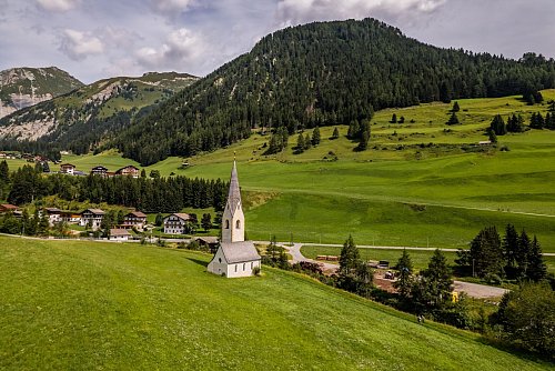 Blickfang auf der grünen Wiese: die Kapelle St. Georg in Kals am Großglockner. - © Peter Maier/Tirol Werbung/dpa-tmn