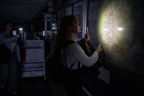 Eine Frau behilft sich mit der Taschenlampe ihres Handys, um den Plan des Madrider U-Bahn-Netzes anschauen zu können. - © Alejandro Martínez Vélez/EUROPA PRESS/dpa