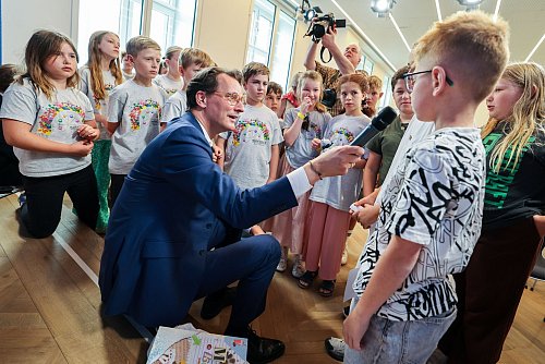 NRW-Ministerpräsident Hendrik Wüst (CDU) hält bei Fragen der Kinderreporter auch mal selbst das Mikrofon. - © Christoph Reichwein/dpa