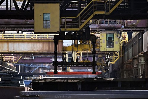 Noch glühend heiß wird eine sogenannte Bramme in einer großen Walzmaschine zu Spezialblech weiterverarbeitet. - © Federico Gambarini/dpa