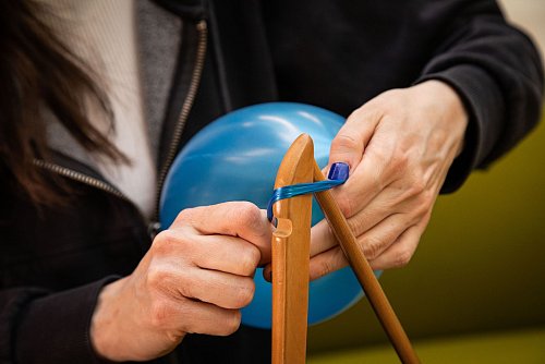 Schritt 1: Den Hals des Luftballons um ein Ende des Kleiderbügels wickeln. - © Christin Klose/dpa-tmn