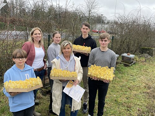 Angelika Galen (3. v. r.) holt die Honig-Lieferung an der Sekundarschule ab. Lehrerin Julia Daldrup und der Vorstand der Schülgenossenschaft mit Siebtklässler Theo (v. l.) sowie Lena, Noah und Magnus aus dem zehnten Jahrgang überreichen außerdem eine Bienen-Patenschaft. - © Tasja Klusmeyer