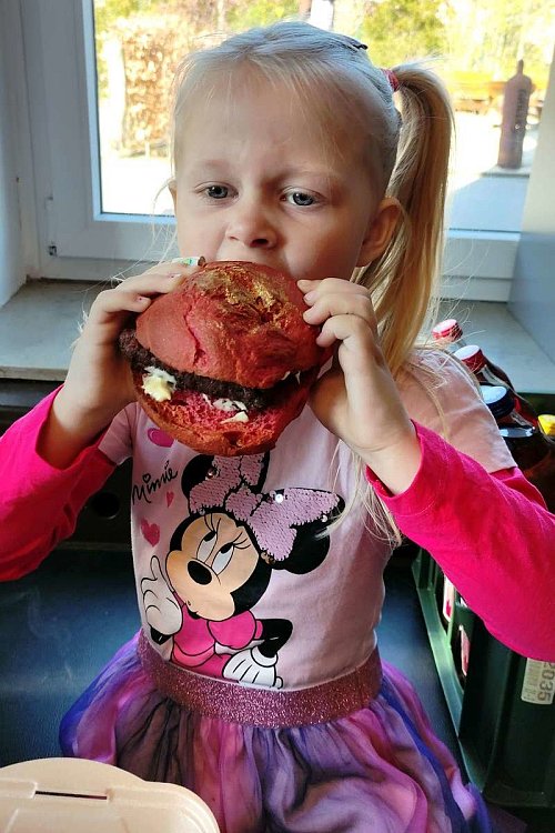 Die fünfjährige Feelia Summer Blume beißt sich durch ihren pinkfarbenen, mit goldenem Feenstaub bestäubten Hamburger. - © Edwin Rekate