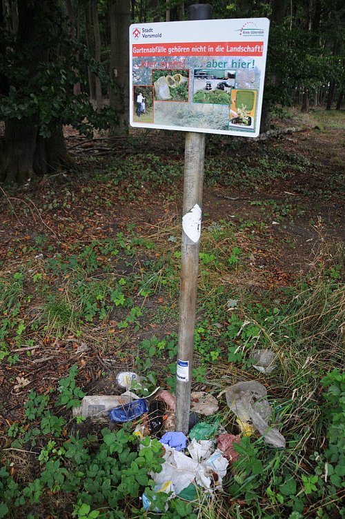 Verpackungsmüll von mittäglichen Pausen sind am Schild mit dem Hinweis dass Gartenabfälle nicht in die Natur gehören, zu finden. - © Tasja Klusmeyer, HK