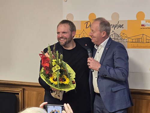 Veith Lemmen bleibt Bürgermeister in Werther. Wahlleiter Guide Neugebauer (r.) gratuliert seinem alten und neuen Chef mit einem großen Blumenstrauß. - © Silke Derkum-Homburg