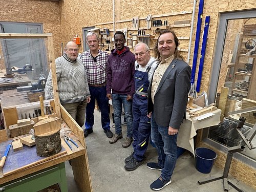Heiko Witte, Vorsitzender des Versmolder Gewerbevereins (r.), lässt sich die Werkbude zeigen. Wolf Hollmann (Fachbereich Sprache, v. l.) , Cesario Giotta (Fachbereich Metall), Teilnehmer Djanfara Cisse und Peter Grimkowski (Vorsitzender) zeigen ihm die Werkstätten an der Knetterhauser Straße. - © Tasja Klusmeyer