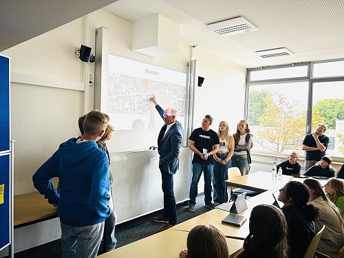 Bürgermeister Thomas Tappe, einst selbst Schüler am KGH, erklärte die von den Schülern genannten Fallbeispiele direkt an einer Stadtkarte. - © Tobias Barrelmeyer
