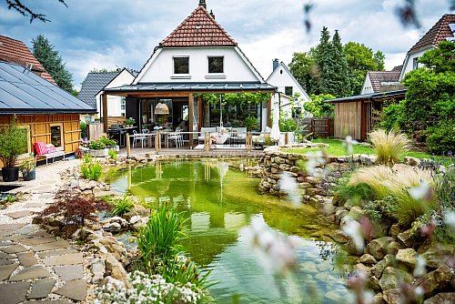Der Blick fällt vom Teich auf das Haus mit der schicken Holzterrasse. - © Barbara Franke