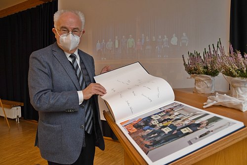 Mit einem von Profifotograf Jan Düfelsiek gestalteten Bildband verabschieden sich die Rathausmitarbeitern von Klaus Besser. Auf der Leinwand des festlich dekorierten Ratssaals laufen derweil die Motives des Buches im Großformat. - © Jonas Damme